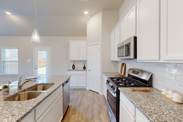 kitchen featuring stainless steel appliances, sink, decorative light fixtures, white cabinets, and light stone counters