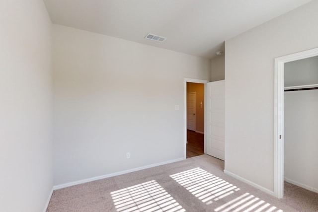 unfurnished bedroom featuring a closet and light colored carpet