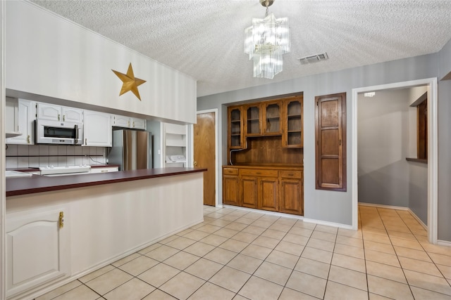 kitchen with stainless steel fridge, a chandelier, pendant lighting, decorative backsplash, and white cabinets