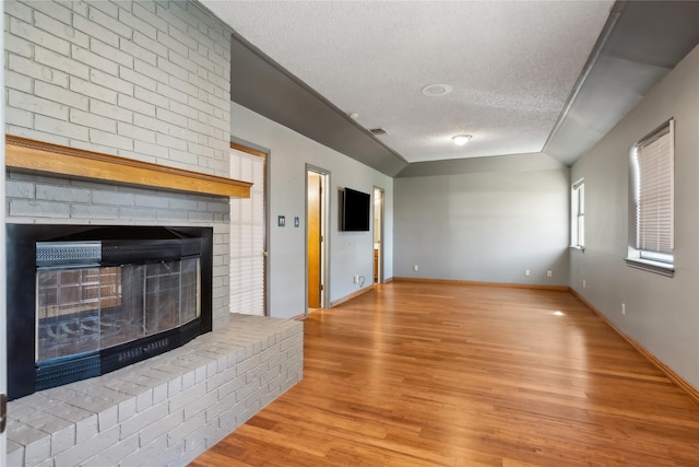 unfurnished living room with a fireplace, a textured ceiling, and light wood-type flooring