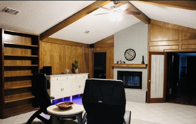 home office featuring ceiling fan, lofted ceiling with beams, wooden walls, a fireplace, and light tile patterned floors