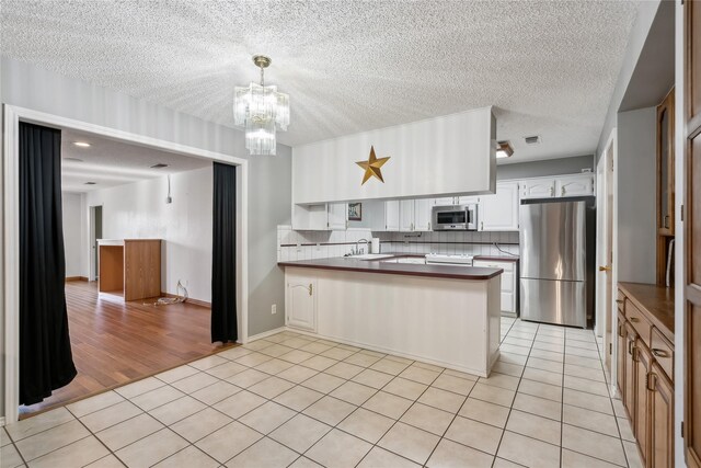 kitchen with backsplash, stainless steel appliances, white cabinetry, and sink