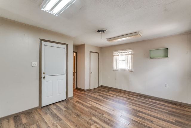 spare room featuring a textured ceiling and dark hardwood / wood-style floors