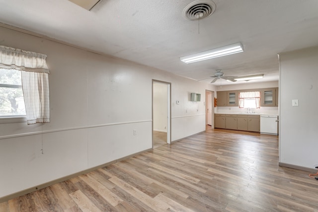 unfurnished living room featuring sink, ceiling fan, light wood-type flooring, and a textured ceiling