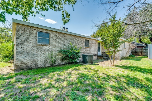 rear view of property featuring cooling unit and a yard