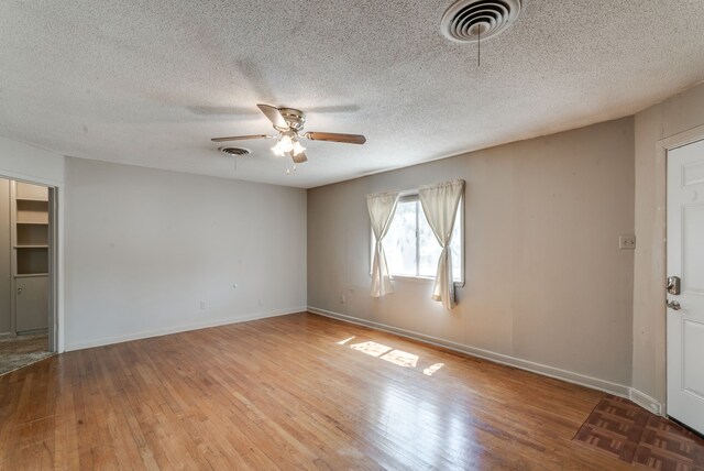 unfurnished room featuring a textured ceiling, ceiling fan, and light hardwood / wood-style floors