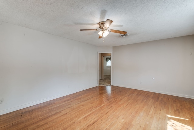 unfurnished room with a textured ceiling, light wood-type flooring, and ceiling fan