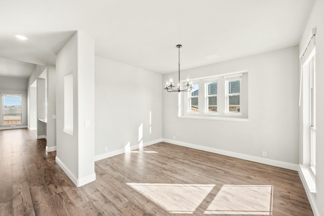 unfurnished dining area featuring an inviting chandelier and wood-type flooring