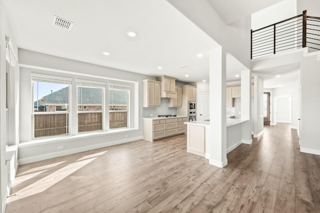 kitchen featuring light hardwood / wood-style floors, stainless steel appliances, light brown cabinetry, and tasteful backsplash