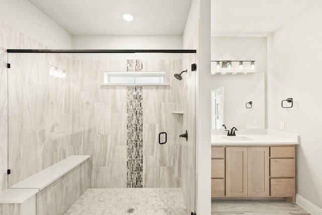 bathroom featuring a shower with shower door and vanity