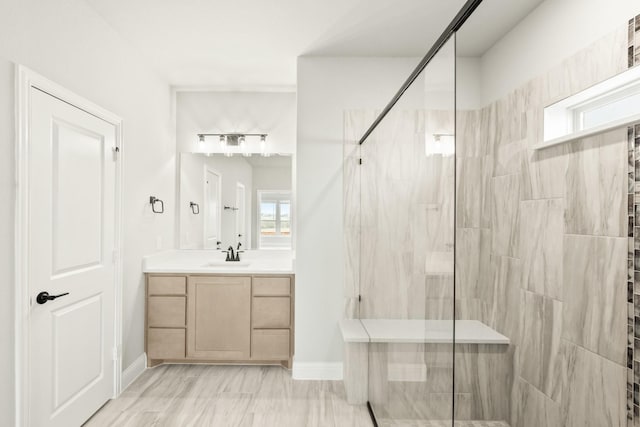 bathroom with a tile shower, vanity, and a wealth of natural light