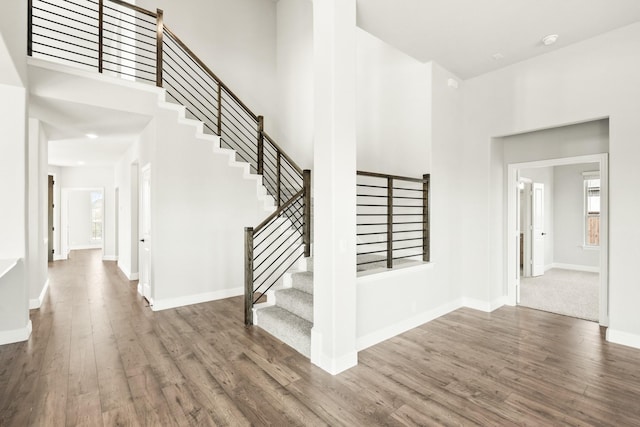 staircase featuring dark wood-type flooring and a high ceiling