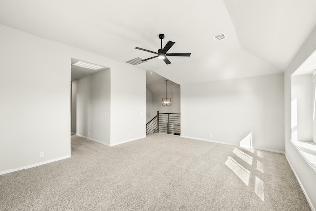 carpeted spare room featuring vaulted ceiling and ceiling fan