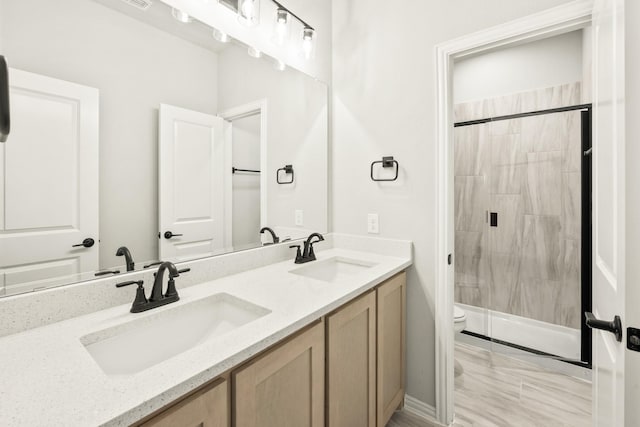 bathroom with toilet, vanity, and a shower with shower door