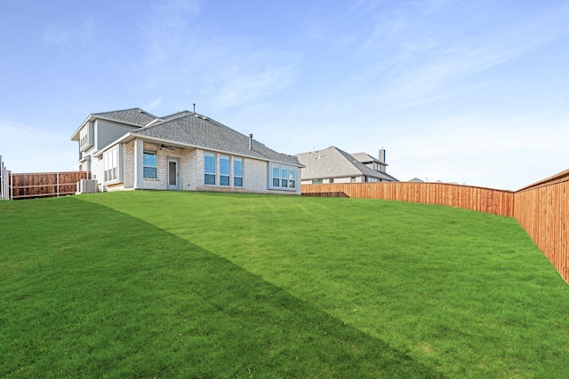 rear view of house with a yard and central AC