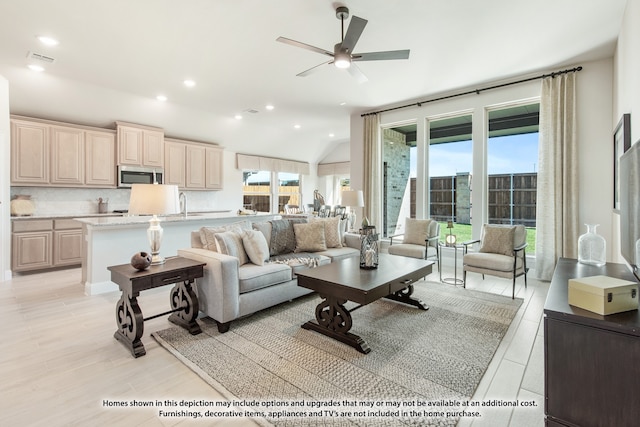 living room featuring a wealth of natural light, vaulted ceiling, ceiling fan, and light hardwood / wood-style floors