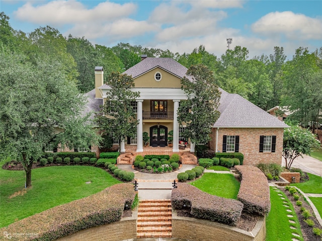 view of front facade with a balcony and a front lawn