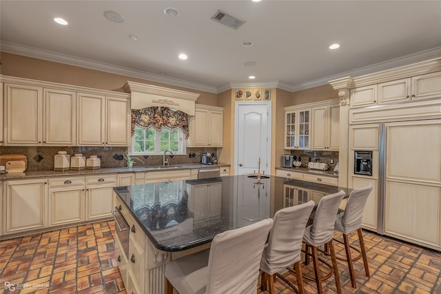 kitchen featuring paneled fridge, a center island, sink, and cream cabinetry