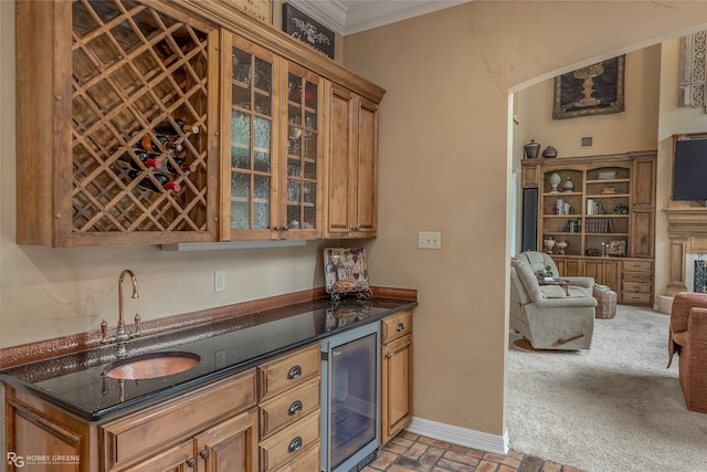 kitchen with dark stone countertops, ornamental molding, sink, and wine cooler