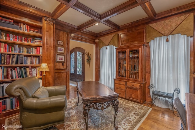 living area with coffered ceiling, light wood-type flooring, and wood walls