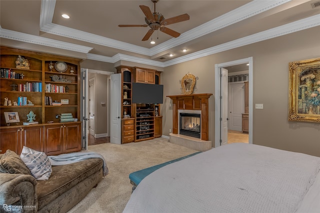 bedroom with a multi sided fireplace, crown molding, a tray ceiling, ceiling fan, and light colored carpet