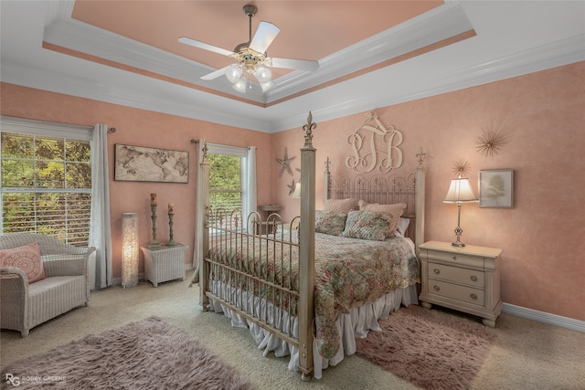 bedroom with a tray ceiling, ceiling fan, light colored carpet, and crown molding