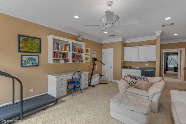 living room featuring ornamental molding, built in desk, ceiling fan, and light carpet