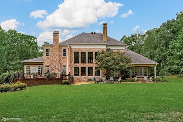 rear view of house featuring a wooden deck and a yard