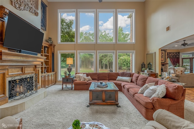 living room with ceiling fan, a fireplace, a high ceiling, and a wealth of natural light