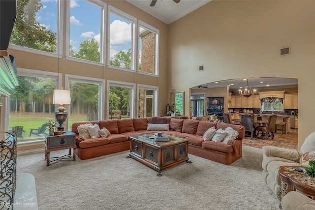 living room with ceiling fan with notable chandelier, a high ceiling, and crown molding