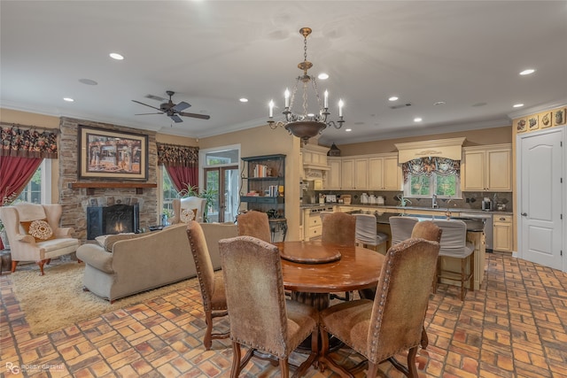 dining room featuring ceiling fan with notable chandelier, a fireplace, and ornamental molding