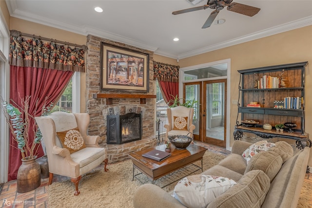 living room with a stone fireplace, ceiling fan, french doors, and crown molding