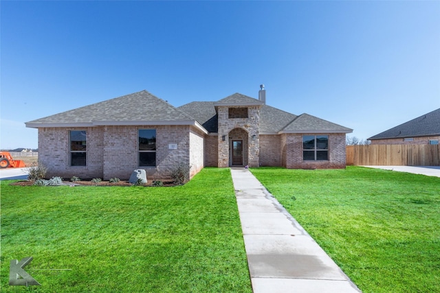 view of front of property featuring fence, a front lawn, and brick siding