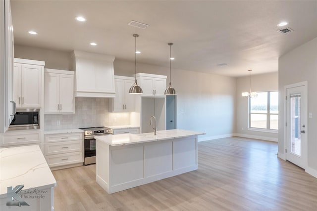 kitchen featuring built in microwave, visible vents, stainless steel range with electric cooktop, and premium range hood