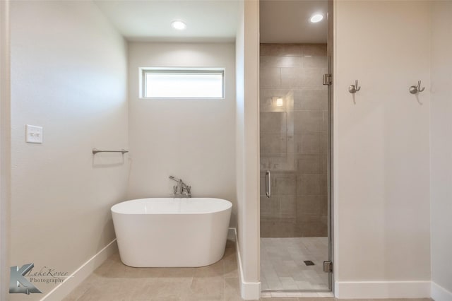 full bath featuring a stall shower, tile patterned flooring, baseboards, and a freestanding tub