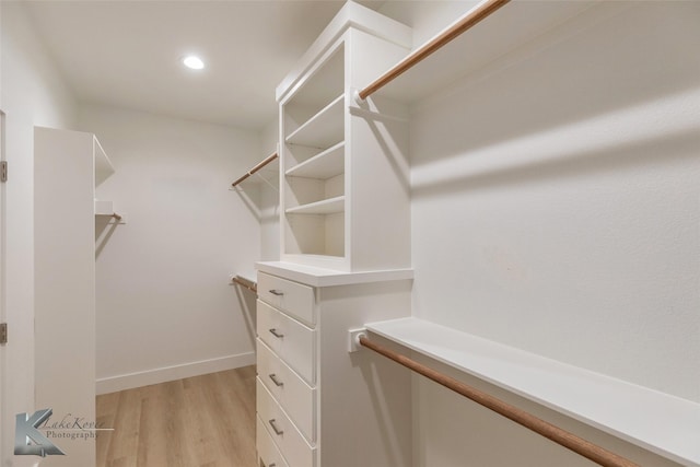 walk in closet with light wood finished floors