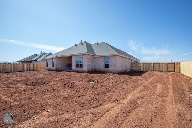 back of house with a fenced backyard and brick siding