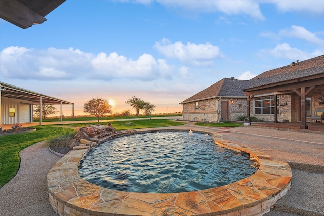 pool at dusk with a hot tub, pool water feature, and a patio area