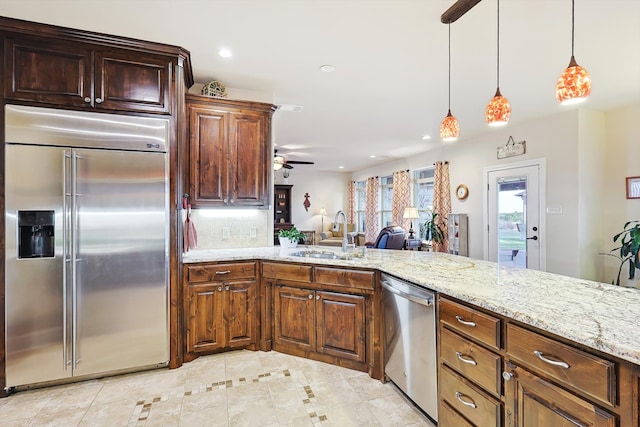 kitchen with tasteful backsplash, stainless steel appliances, pendant lighting, sink, and ceiling fan