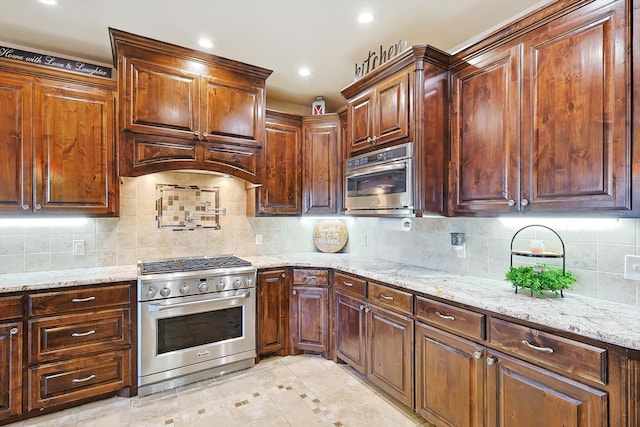 kitchen with appliances with stainless steel finishes, tasteful backsplash, and light stone countertops