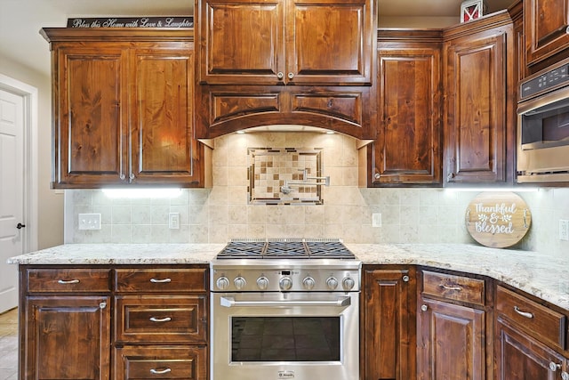 kitchen with appliances with stainless steel finishes, backsplash, and light stone countertops