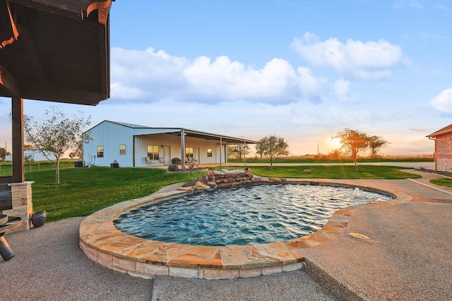 pool at dusk featuring a lawn and a patio area