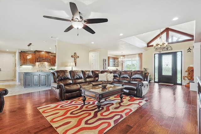 living room featuring light wood-type flooring, vaulted ceiling, and ceiling fan with notable chandelier