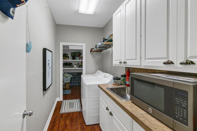 laundry room featuring cabinets, sink, dark wood-type flooring, and washing machine and dryer