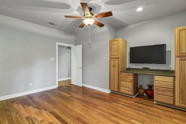 interior space featuring ceiling fan, built in desk, and light hardwood / wood-style floors