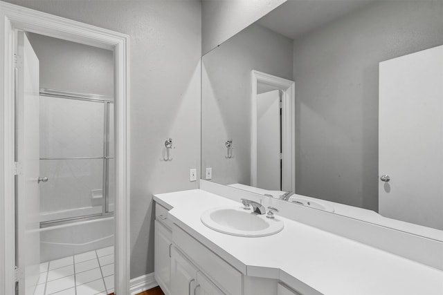 bathroom with enclosed tub / shower combo, vanity, and tile patterned flooring