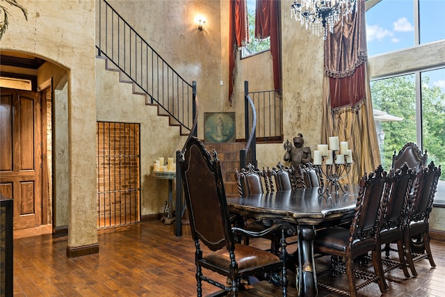 dining space with dark hardwood / wood-style floors, a chandelier, and a towering ceiling