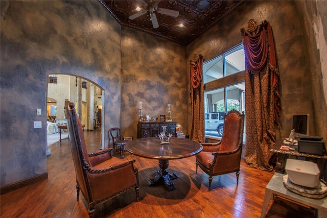 living area with hardwood / wood-style flooring, a towering ceiling, and ceiling fan