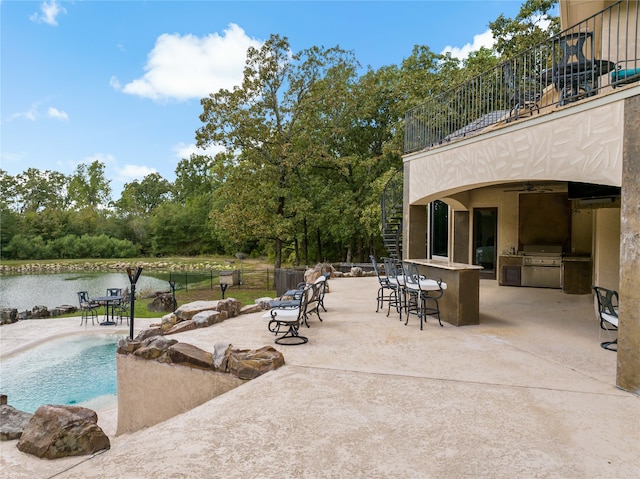 view of pool featuring a water view, a grill, a patio area, area for grilling, and a bar