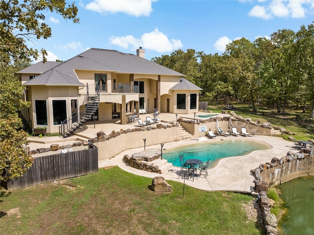 back of property featuring a swimming pool with hot tub, a lawn, a patio, and a balcony